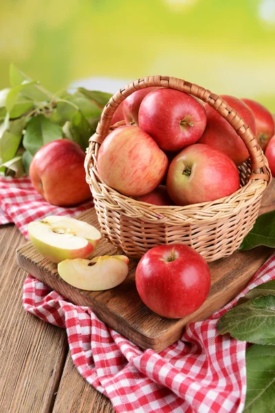 Sweet apples in wicker basket on table on bright background — Stock Photo, Image