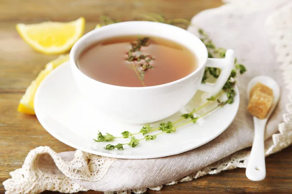 Tasse leckeren Kräutertee mit Thymian und Zitrone auf Holztisch — Stockfoto