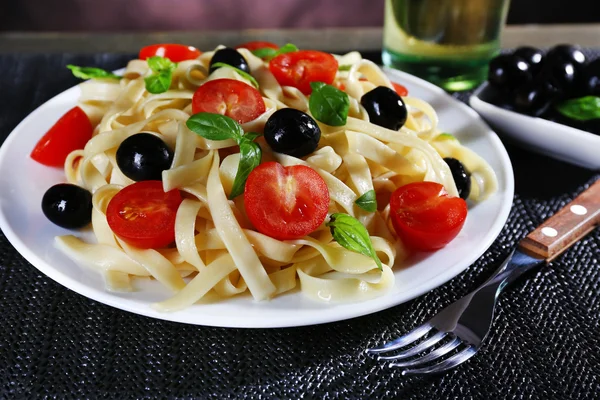 Espaguetis con tomates, aceitunas y hojas de albahaca en primer plano — Foto de Stock