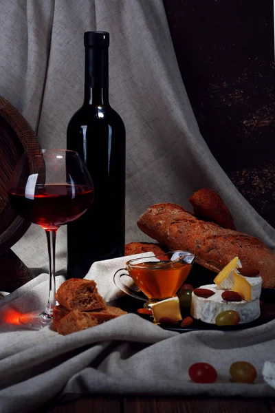 Cena compuesta de queso Camembert y Brie, miel, vino y uvas sobre servilleta y barril de vino sobre fondo cortina —  Fotos de Stock