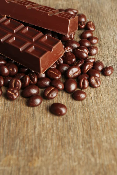 Kávová zrna s čokoládovou polevou a tmavá čokoláda na dřevěné pozadí — Stock fotografie