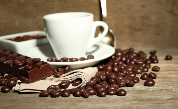 Taza de café y granos de café con esmalte de chocolate sobre fondo de madera — Foto de Stock