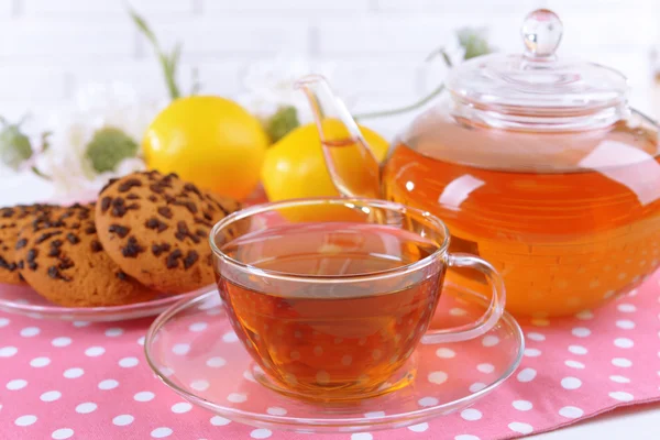 Bule e xícara de chá na mesa no fundo da parede de tijolo — Fotografia de Stock
