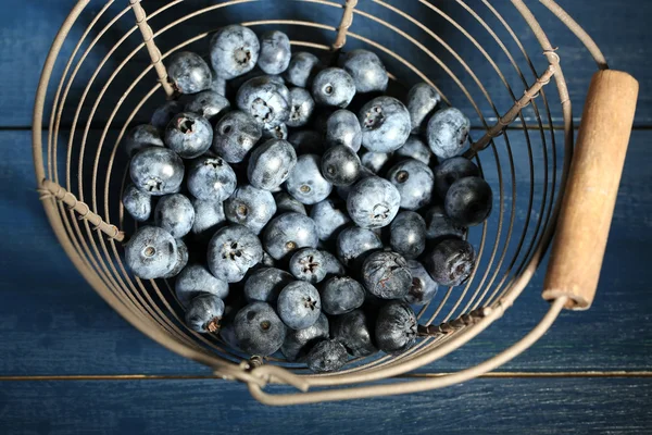 Leckere reife Blaubeeren im Metallkorb, auf Holzgrund — Stockfoto