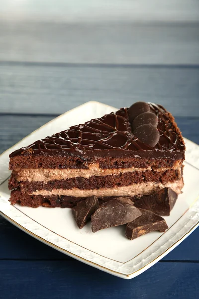 Schokoladenkuchen auf Teller auf farbigem Holzhintergrund — Stockfoto