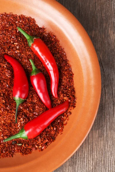 Red hot chili peppers ve ahşap arka plan üzerinde plaka üzerinde öğütülmüş karabiber — Stok fotoğraf