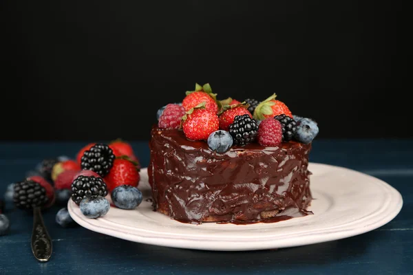 美味的巧克力蛋糕，与不同的莓果，木制的桌子，在深色背景上 — 图库照片