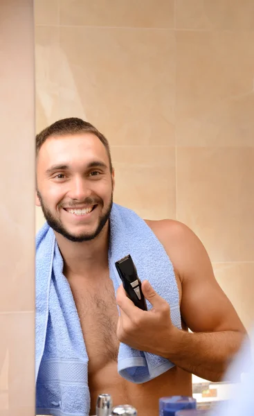 Jongeman scheren zijn baard in badkamer — Stockfoto