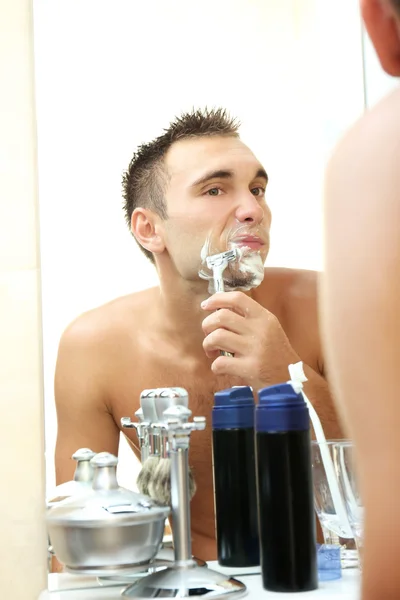 Jovem barbear sua barba no banheiro — Fotografia de Stock