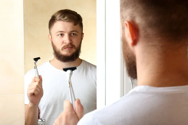 Jovem barbear sua barba no banheiro — Fotografia de Stock