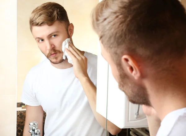 Mladý muž holení jeho vousy v koupelně — Stock fotografie