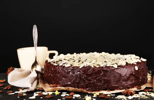 Tasty chocolate cake with almond, on wooden table, on dark background — Stock Photo, Image