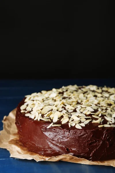 Leckere Schokoladenkuchen mit Mandeln, auf Holztisch, auf dunklem Hintergrund — Stockfoto