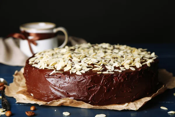 Kue coklat lezat dengan almond, di atas meja kayu, di latar belakang gelap — Stok Foto