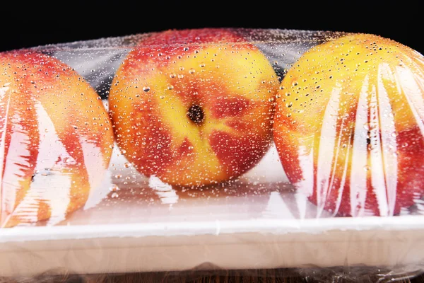 Peaches packed in food film on table close-up — Stock Photo, Image