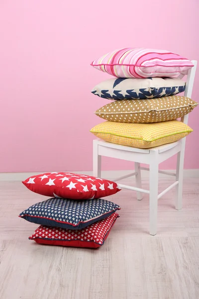 Almohadas brillantes en la silla en la habitación sobre fondo rosa — Foto de Stock