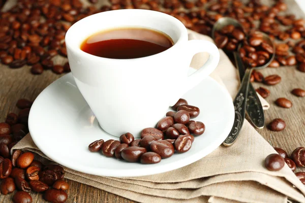 Kopp kaffe och kaffebönor med choklad glasyr på trä bakgrund — Stockfoto