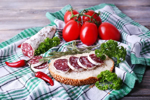 Fransk salami med bröd, tomater och persilja på tyg bakgrund — Stockfoto