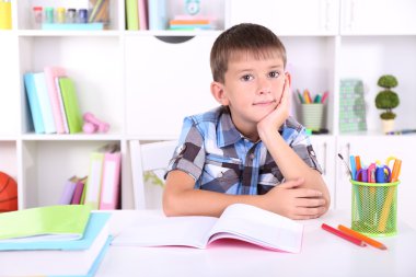 школяр, сидячи на столі в класі