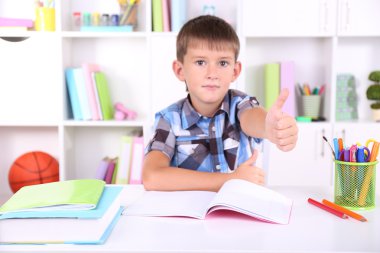 школяр, сидячи на столі в класі