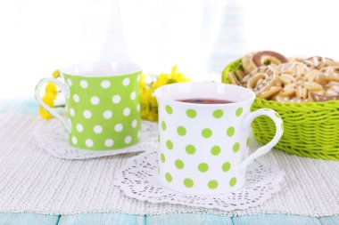 İki benekli çay fincanı ve perde arkasında bisküviler.