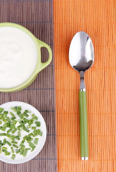 Green pan and plastic bowl of cream with onion on a napkin — Stock Photo, Image