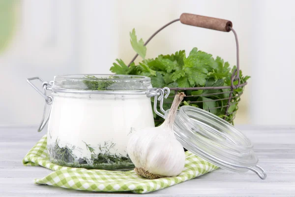 Glass round bowl of cream with a tuft of dill and pepper near it on a napkin on a wooden table — Stock Photo, Image