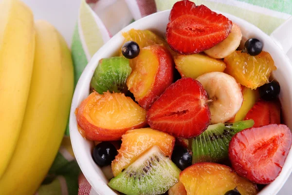 Fresh fruits salad in bowl on napkin close up — Stock Photo, Image