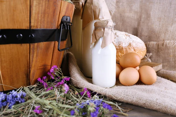 Big round wooden basket with vegetables, milk and bread on sacking background — Stock Photo, Image