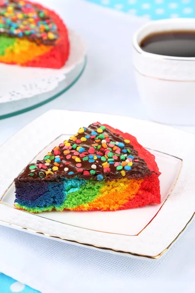 Heerlijke regenboogcake op plaat, op tafellaken achtergrond — Stockfoto