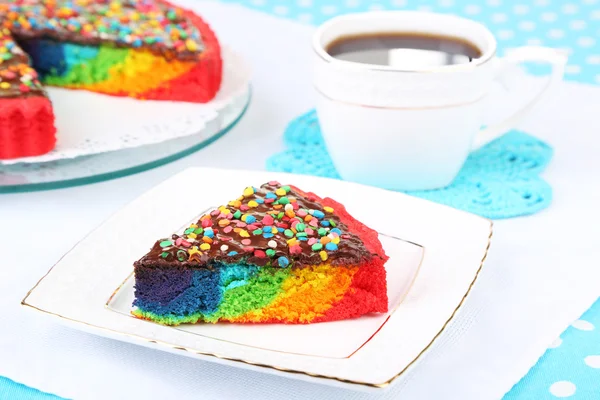 Delicioso pastel de arco iris en el plato, sobre fondo de mantel — Foto de Stock