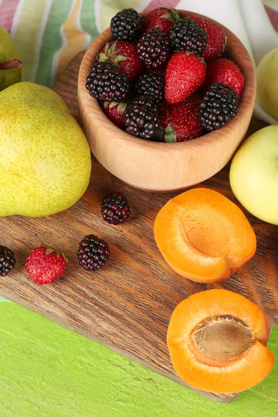 Ripe fruits and berries in bowl on table close up — Stock Photo, Image