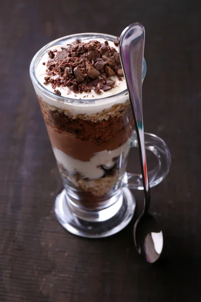 Yogourt, à la crème au chocolat, chocolat haché et muesli servi en verre sur fond de bois — Photo