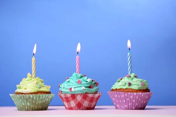 Deliciosos cupcakes de cumpleaños en la mesa sobre fondo azul —  Fotos de Stock