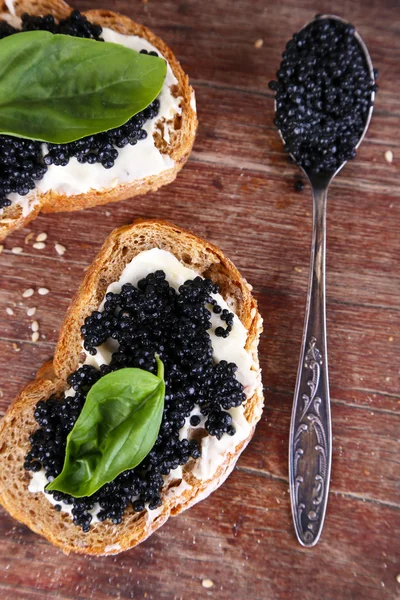 Tranches de pain au beurre et caviar noir sur fond de bois — Photo
