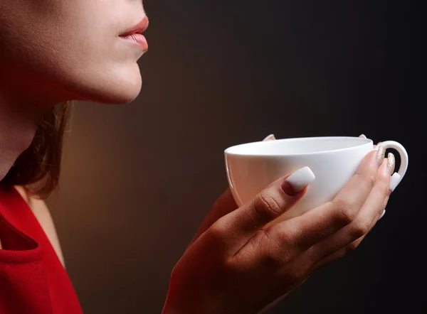 Mooi meisje met kop koffie op bruine achtergrond — Stockfoto