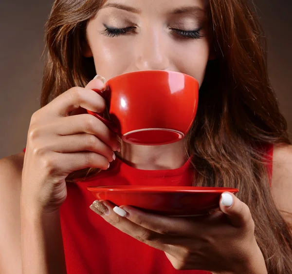 Красивая молодая девушка с чашкой кофе на коричневом фоне — стоковое фото