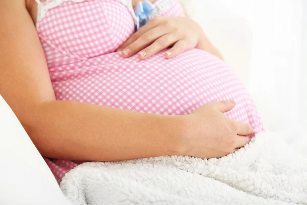 Молодая беременная женщина лежит на диване в комнате — стоковое фото