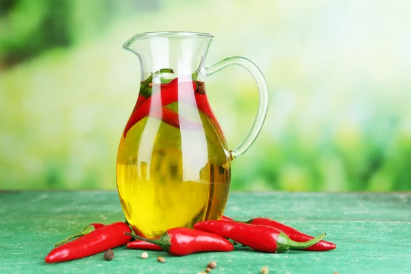 Homemade natural infused olive oil with red chili peppers on color wooden table, on bright background — Stock Photo, Image