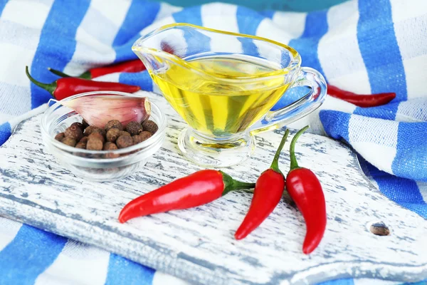 Set of spices and olive oil in glass sauce-boat, in cutting board, on color  wooden background — Stock Photo, Image