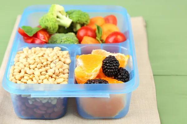 Leckeres vegetarisches Essen in Plastikbox auf grünem Holztisch — Stockfoto