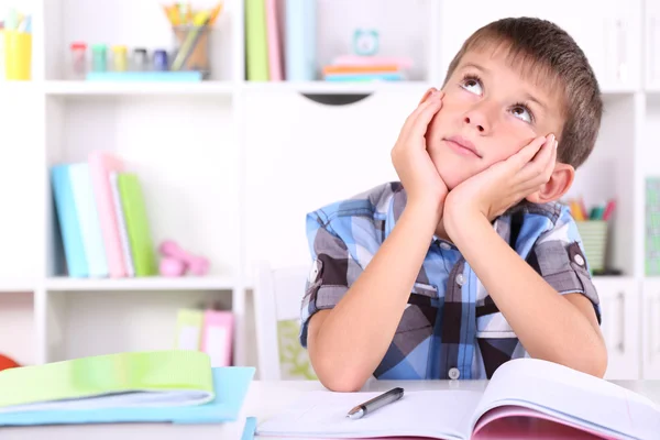 Skolpojke sitter vid bord i klassrummet — Stockfoto