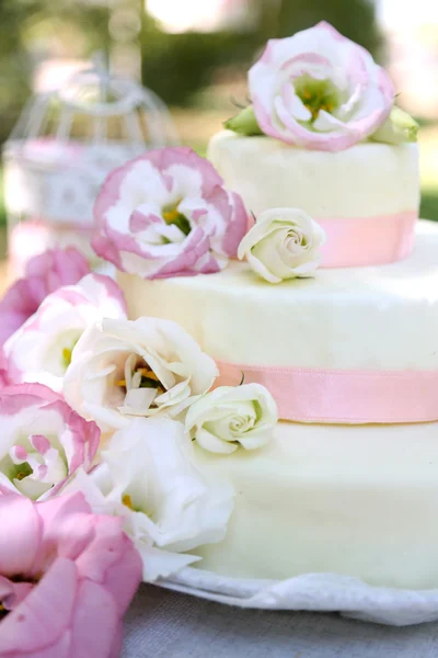 Beautiful wedding cake with flowers on table, outdoors — Stock Photo, Image