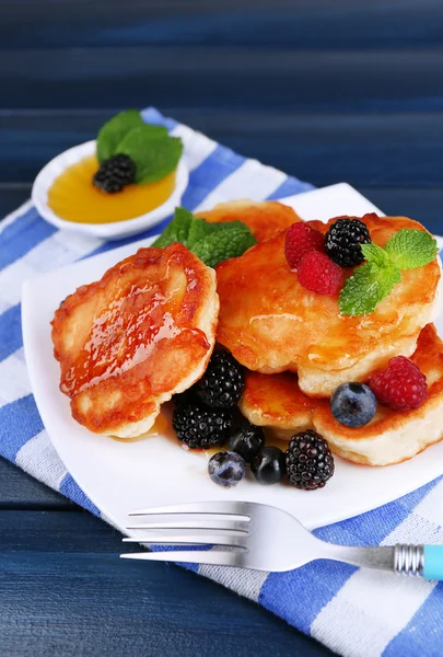 Tasty pancake with fresh berries and mint leaf on plate, on color wooden background — Stock Photo, Image