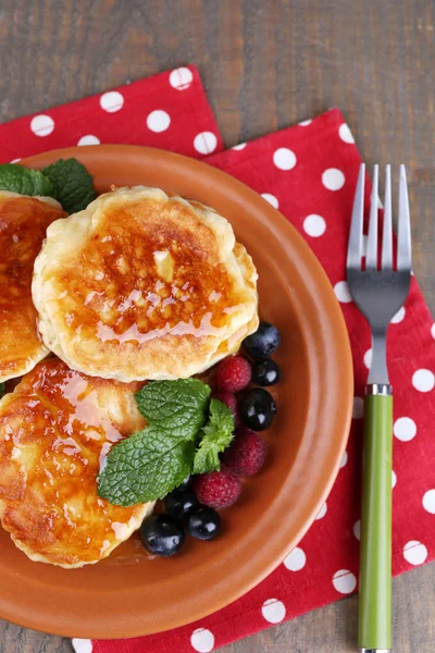 Tasty pancakes with fresh berries, honey and mint leaf on plate, on  wooden background — Stock Photo, Image