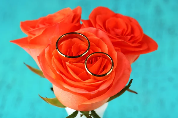 Обручальные кольца на свадебном букете, крупным планом, на ярком фоне — стоковое фото