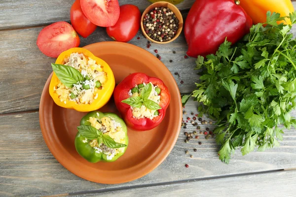 Composition avec poivrons farcis sur assiette et herbes fraîches, épices et légumes, sur fond de bois — Photo