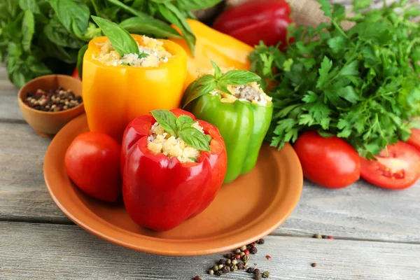 Composition with stuffed peppers on plate and fresh herbs, spices and vegetables, on wooden background — ストック写真