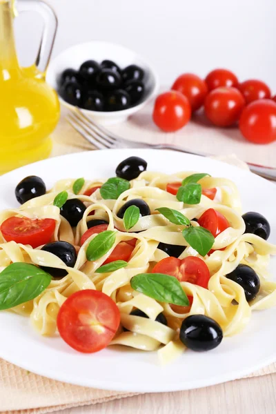 Spaghetti con pomodori, olive, olio d'oliva e foglie di basilico su fondo tessuto — Foto Stock