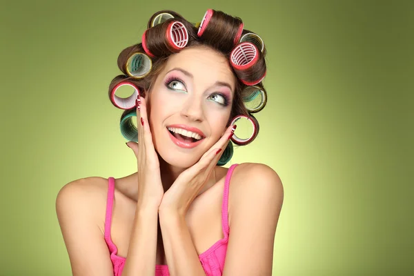 Menina bonita em encrespadores de cabelo no fundo verde — Fotografia de Stock